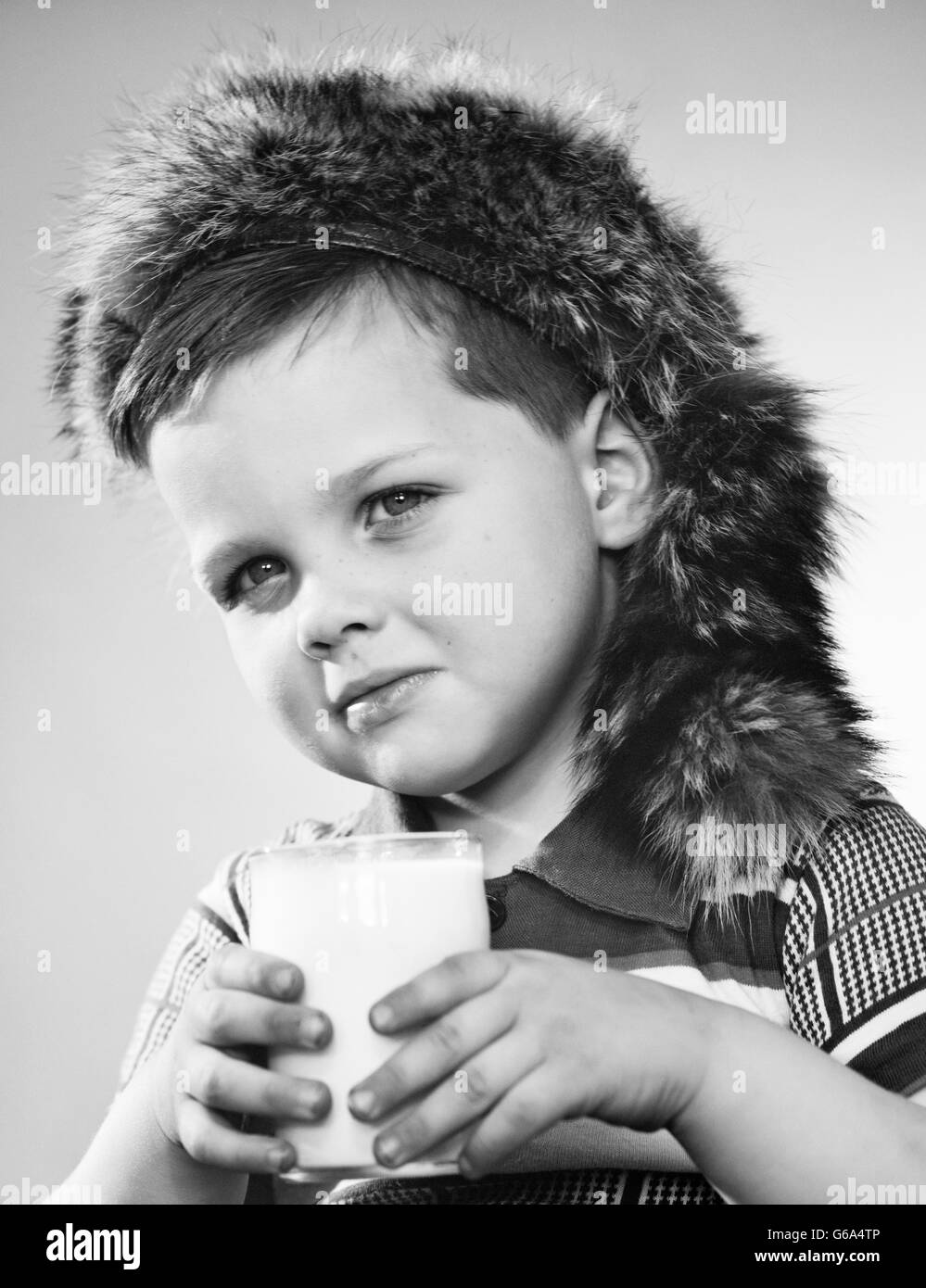 1950s PORTRAIT BOY WEARING DAVY CROCKETT COONSKIN CAP HOLDING GLASS OF MILK LOOKING AT CAMERA Stock Photo