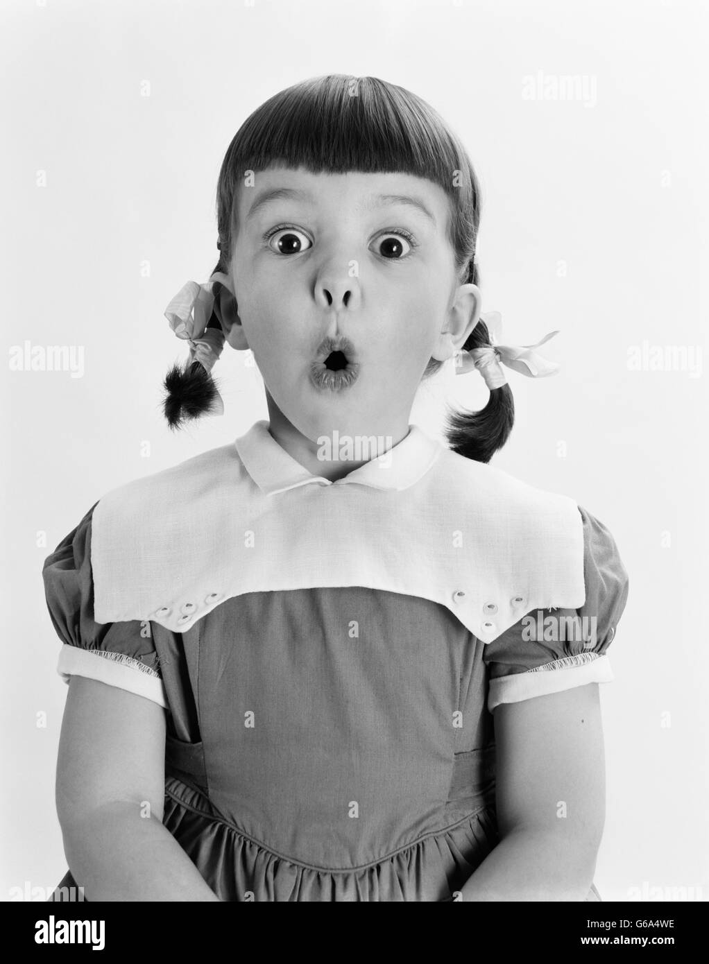 1950s PORTRAIT GIRL HAIR IN PIGTAILS SURPRISED EXPRESSION MOUTH WIDE OPEN LOOKING AT CAMERA Stock Photo