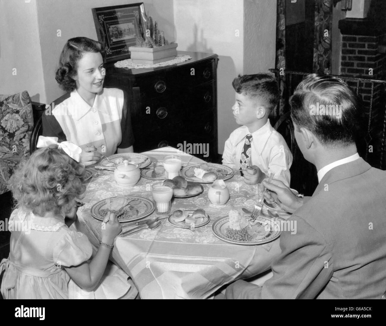 1940s 1950s FAMILY MOTHER FATHER BOY GIRL EATING SUPPER AT DINING TABLE Stock Photo