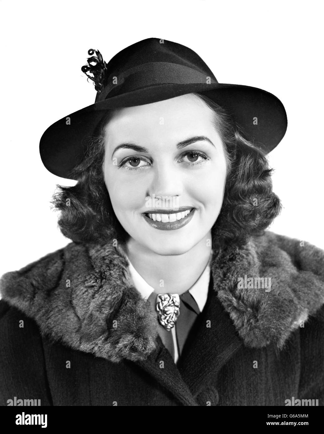 1940s SMILING BRUNETTE WOMAN PORTRAIT WEARING HAT COAT FUR COLLAR LOOKING AT CAMERA Stock Photo