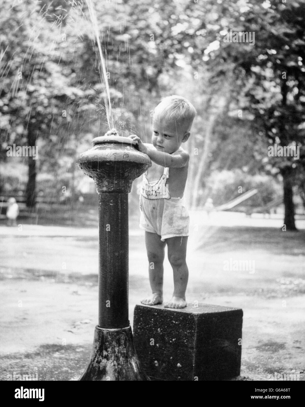 1950s LITTLE BOY PLAYING IN WATER DRINKING FOUNTAIN CENTRAL PARK NYC USA Stock Photo