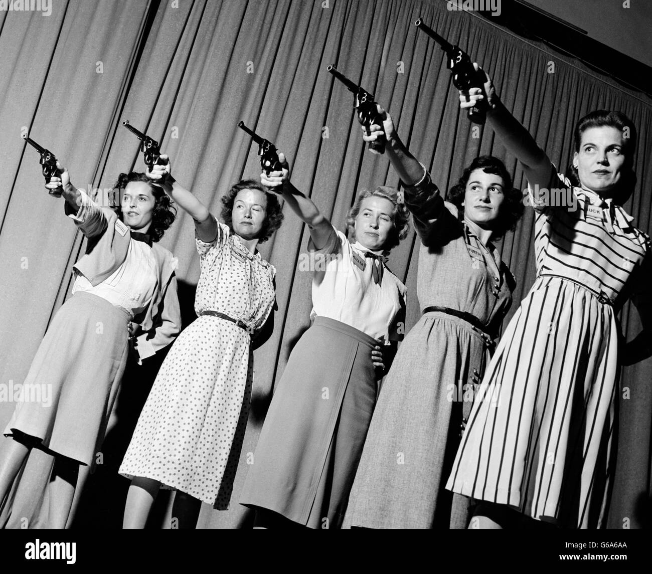 1940s GROUP FIVE WOMEN IN A LINE AIMING PISTOLS Stock Photo