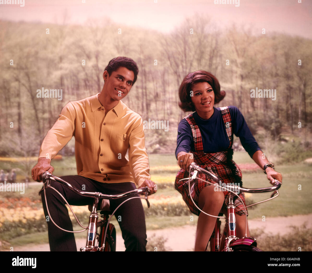 1960s AFRICAN AMERICAN TEENAGE BOY AND GIRL RIDING BICYCLES Stock Photo