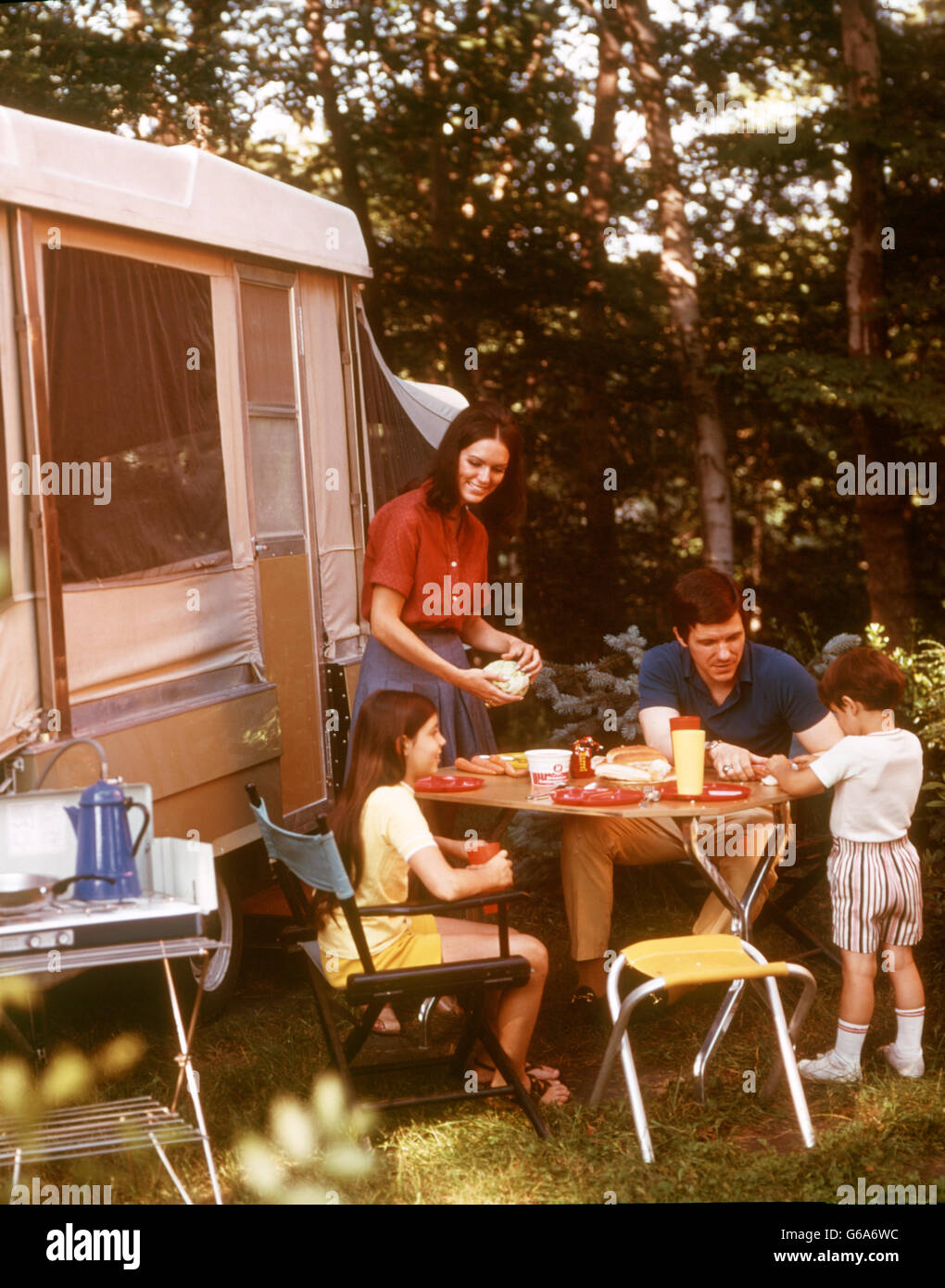 1970s MOTHER SERVING FAMILY MEAL FATHER TWO KIDS OUTSIDE POP-UP CAMPER Stock Photo