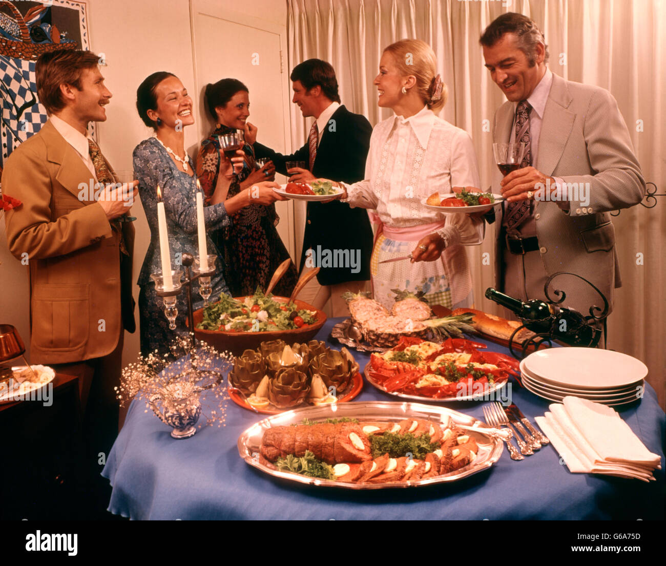 1970s MEN WOMEN COCKTAIL DINNER PARTY BUFFET WOMAN HOSTESS SERVING FOOD DRINKING WINE Stock Photo