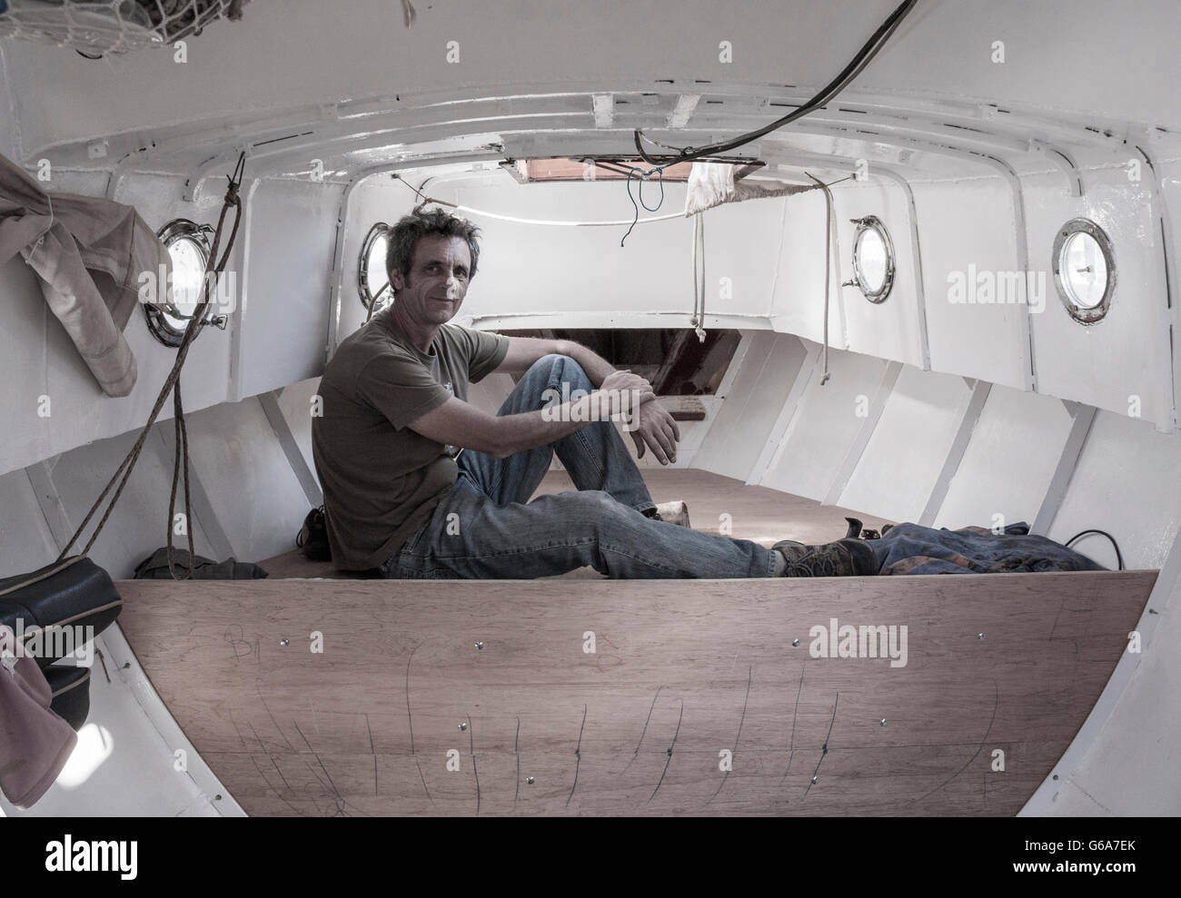 Man refitting interior of steel hulled small yacht Stock 