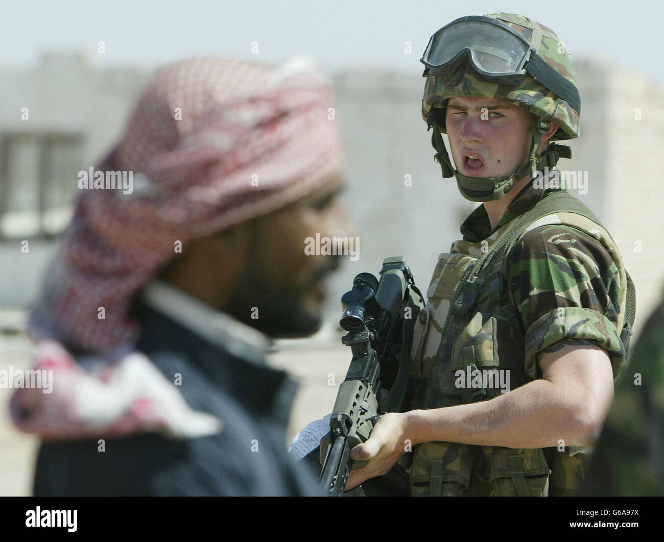 A British soldier watches an Iraqi civilian whilst accompanying REME Captain Ken Jolley on a 'Hearts and Minds' mission. Dan Chung / Guardian / MOD Pool. Stock Photo