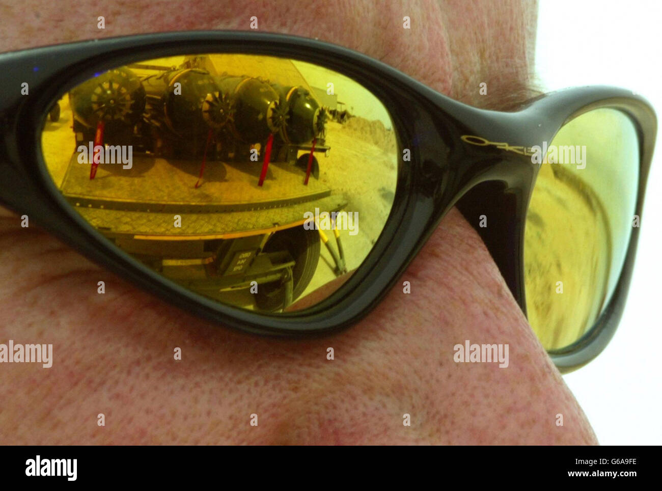 A British Royal Air Force Harrier GR7 engineering technician (propulsion) Darren Dowd has a bomb-trolley of cluster bombs reflected in his sunglasses prior to the bombs being loaded onto an aircraft in Kuwait. *... The United States admits it has used them in Iraq; Britain says it has them, but would not use them in built-up areas; Iraq says they have killed dozens of civilians; and human rights groups insist they should be banned. Cluster bombs are deadly but unpredictable - each contain over 200 bomblets the size of a drinks can which scatter over an area the size of two soccer pitches, Stock Photo