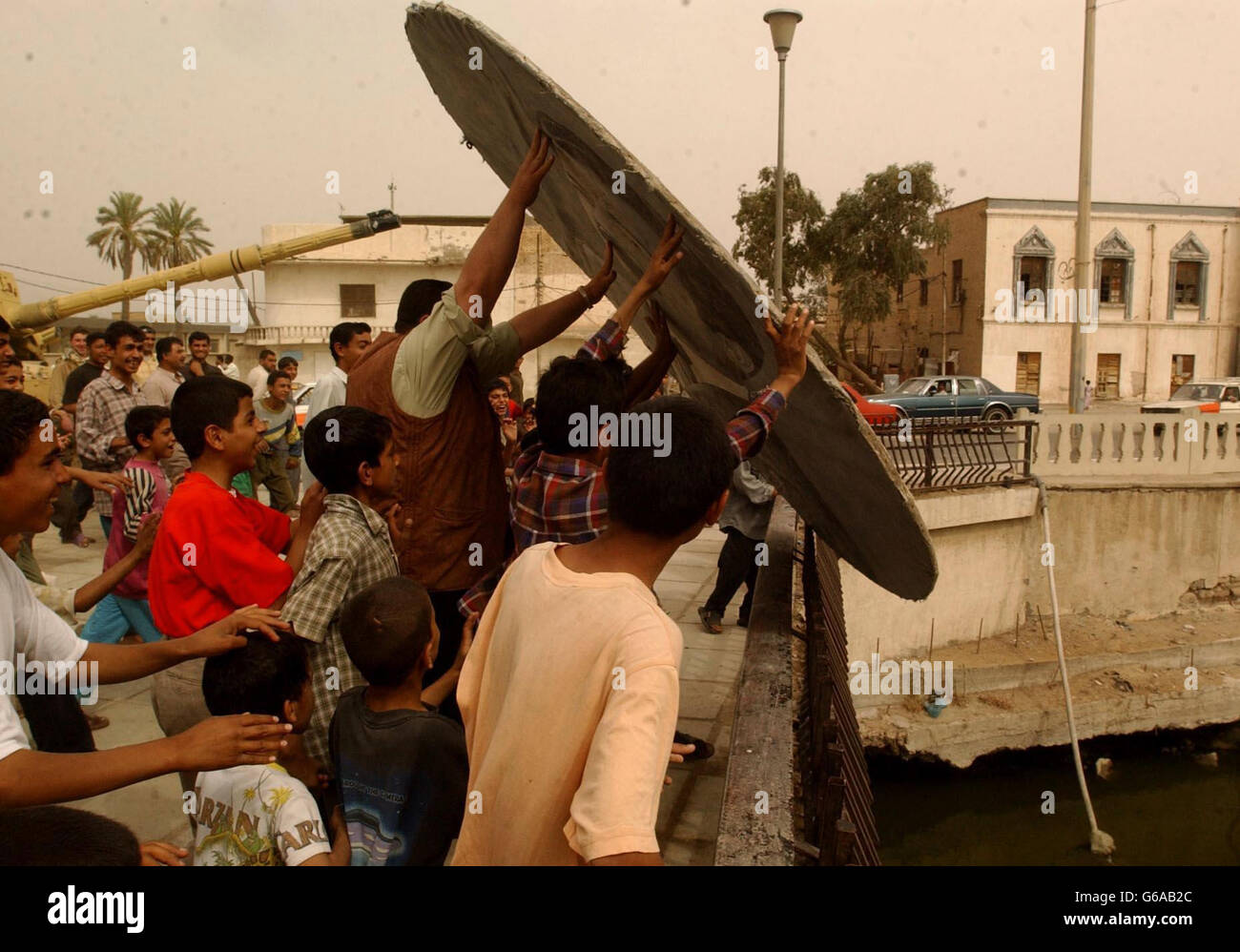 Locals remove a painting of Saddam Hussein in the Irqai town of Basra. Stock Photo