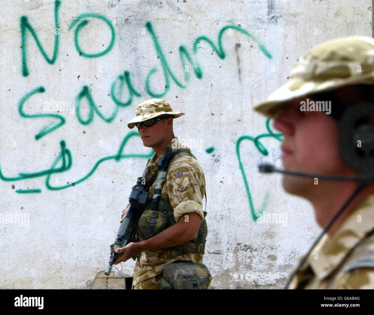Soldiers from 51 Squadron from the British Royal Air Force Regiment patrols past graffiti that says 'No Saddam' in the southern Iraqi town of Safwan. The British forces are helping the local people with humanitarian aid. Stock Photo