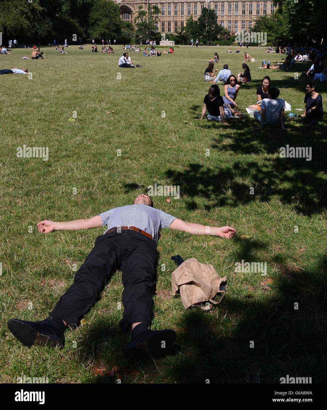 Sunbathers near the Houses of Parliament in London enjoy the hot weather on the first day of August. Stock Photo