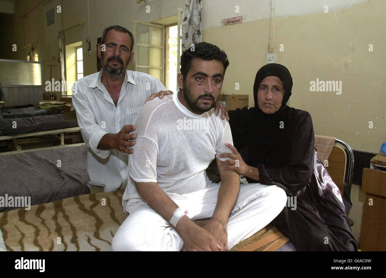 Nagim Abdoul Nabiy, a 25 year-old Iraqi architect, sits with his mother Bahiya Mathood and father Abdouel at Basra General Hospital. His parents fear that he may be dead within two or three days as the hospital has neither blood nor power. Stock Photo