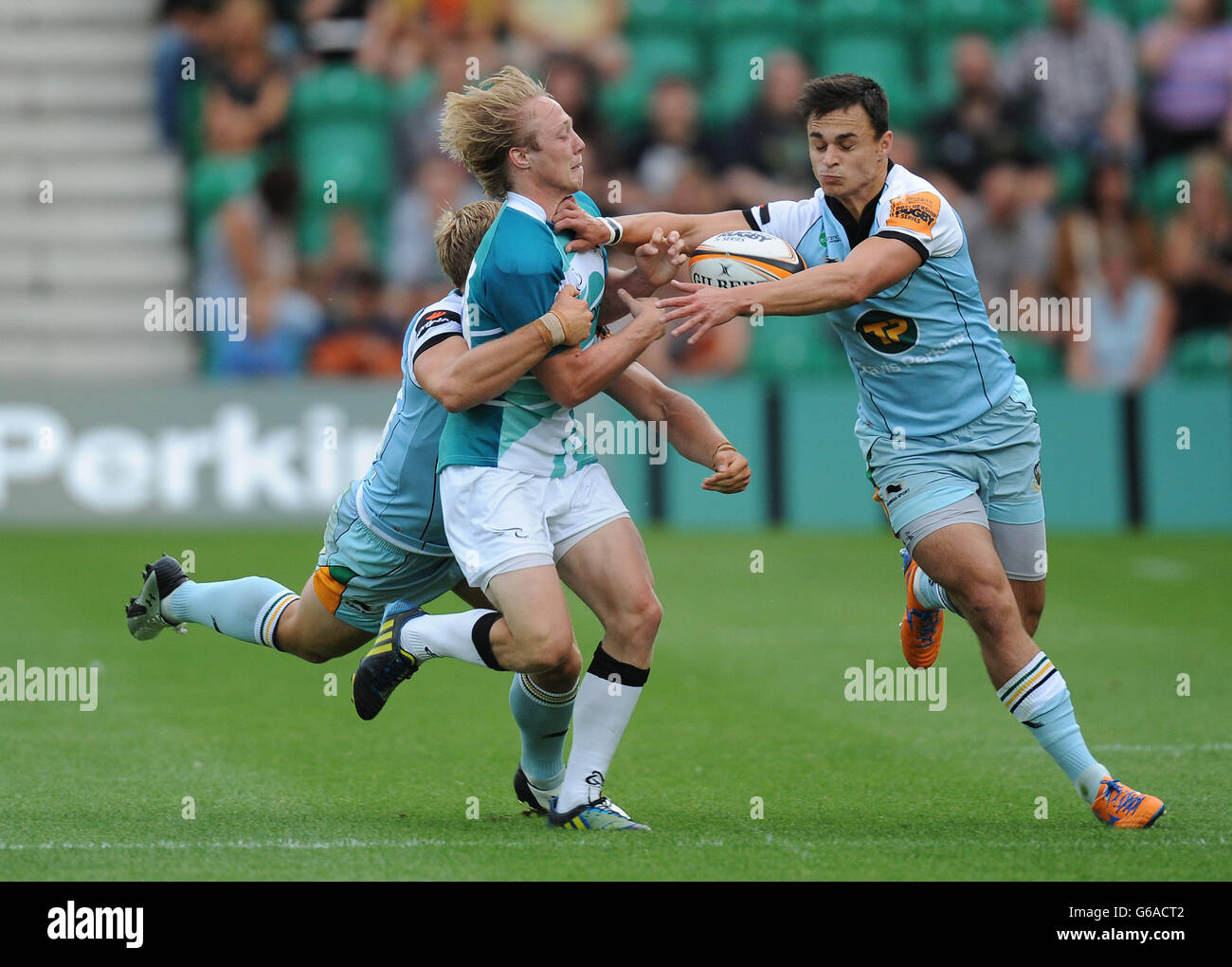 Newcastle Falcons 7's Joel Hodgson (centre) is tackled by Northampton Saints 7's Tom Stephenson (left) and Tom Collins (right) during the Group B match of the J.P. Morgan Asset Management Premiership Rugby 7's at Franklin's Gardens, Northampton. Stock Photo
