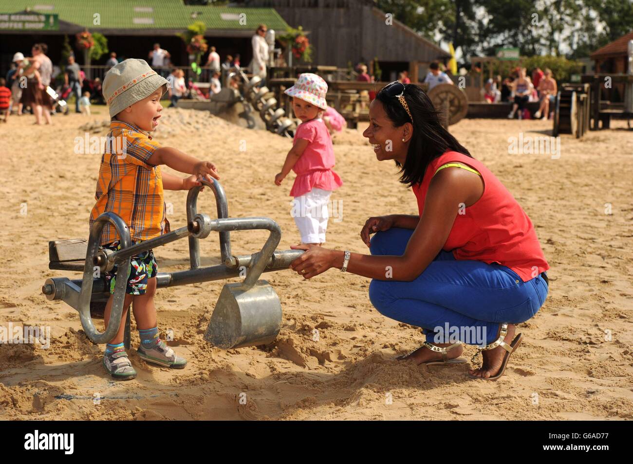 Lucas Hardacre, aged 2, enjoys the sunny weather, with his mother Sheree, in the sand pit at York Maze in North Yorkshire. Stock Photo