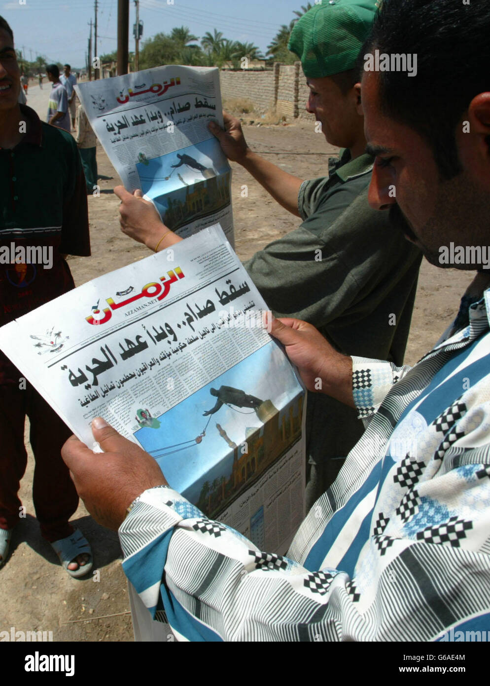 Iraqi people read a newspaper distributed in and around al Qurna by a