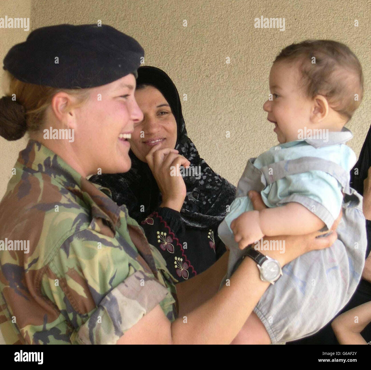 Corporal Claire O'Connor, 26, of Fulham, south west London, from the 2 Close Support Regiment of the Royal Logistic Corps, plays with an Iraqi baby boy at the opening of a primary school in the grounds of a British military base near Basra. * The mixed school - thought to be one of the first to reopen since the start of the war - is on an abandoned military base which is now being used by thousands of British soldiers, and Challenger 2 tanks and Warror fighting vehicles have become familiar sights to the 107 pupils, all aged six to 10. Stock Photo