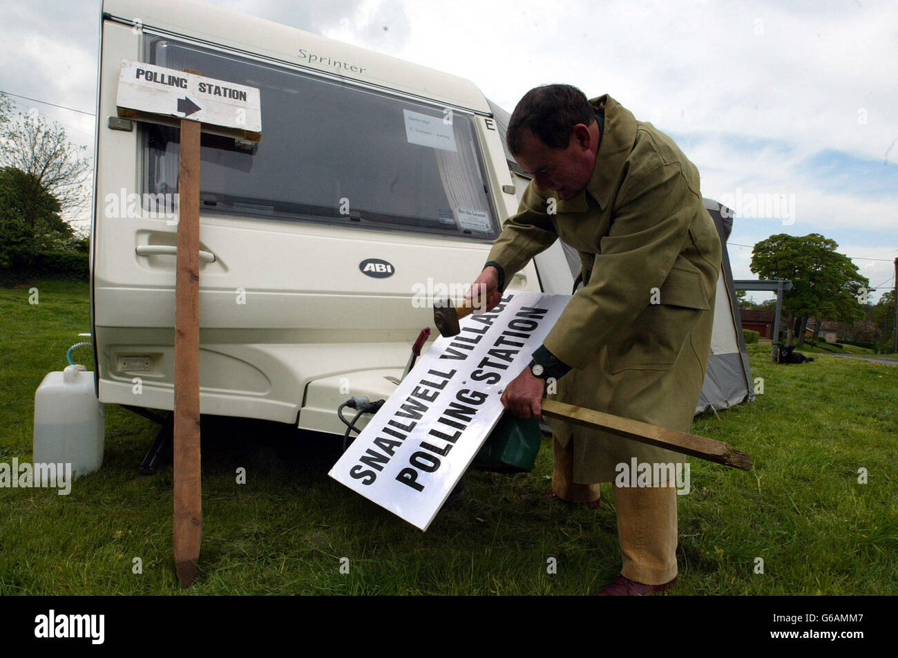 Sean Gallagher East Cambs Election officer putting polling station signs up on village green in Snailwell,Cambridgeshire. for the local elections on Thursday 1st May 2003. Stock Photo