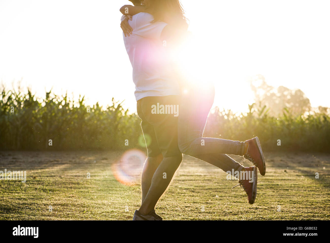 Man embracing and lifting girlfriend into air Stock Photo