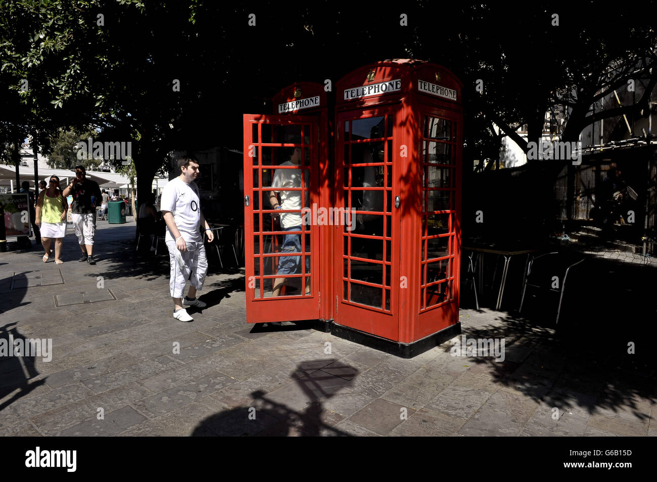 People use the traditional red telephone boxes near Casemates Square, Gibraltar. Stock Photo