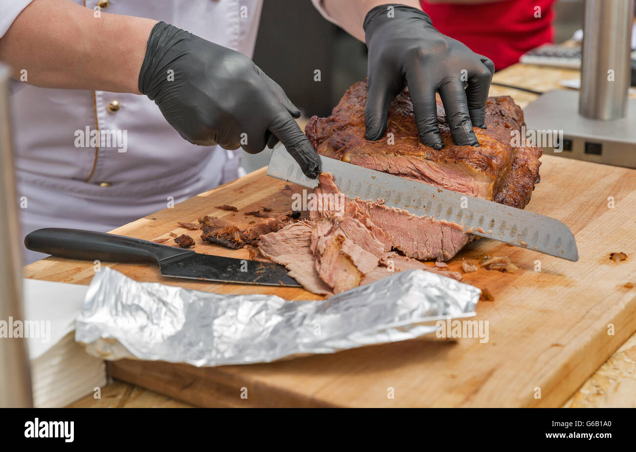 chief cutting thin sliced pastrami beef closeup on cutting board Stock Photo