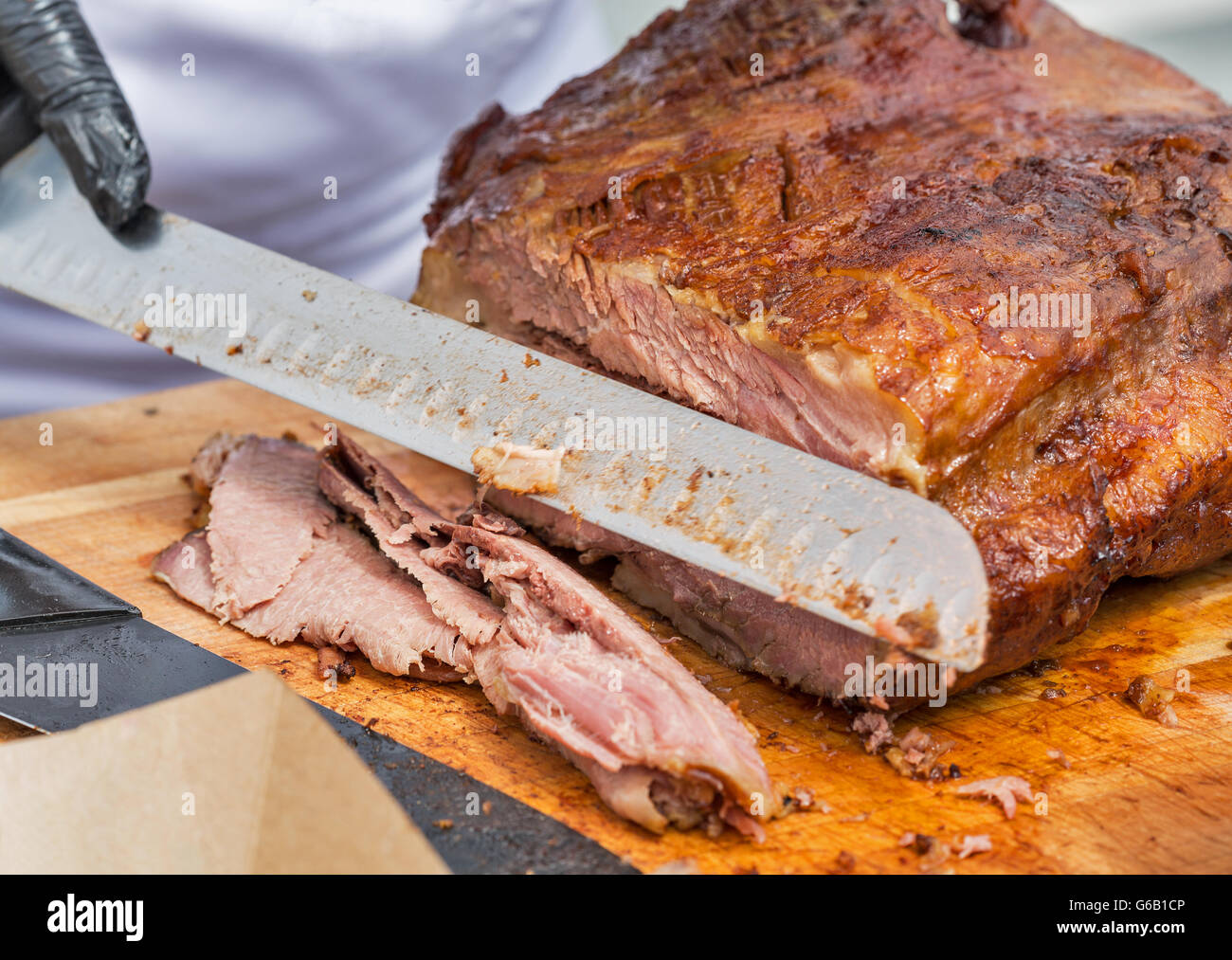 chief cutting thin sliced pastrami beef closeup on cutting board Stock Photo