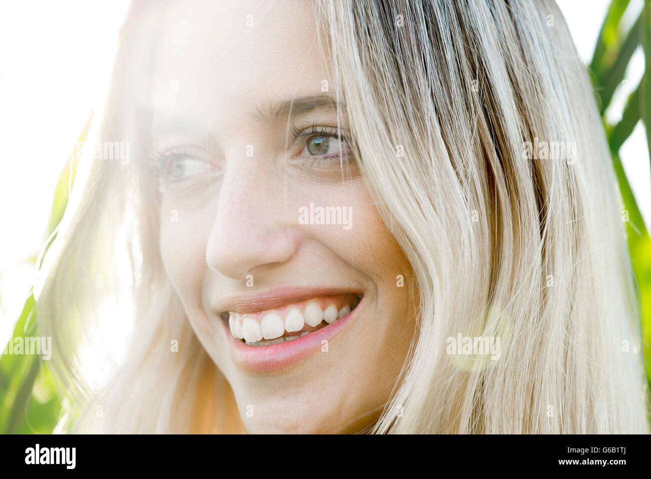 Young woman smiling in thought outdoors Stock Photo