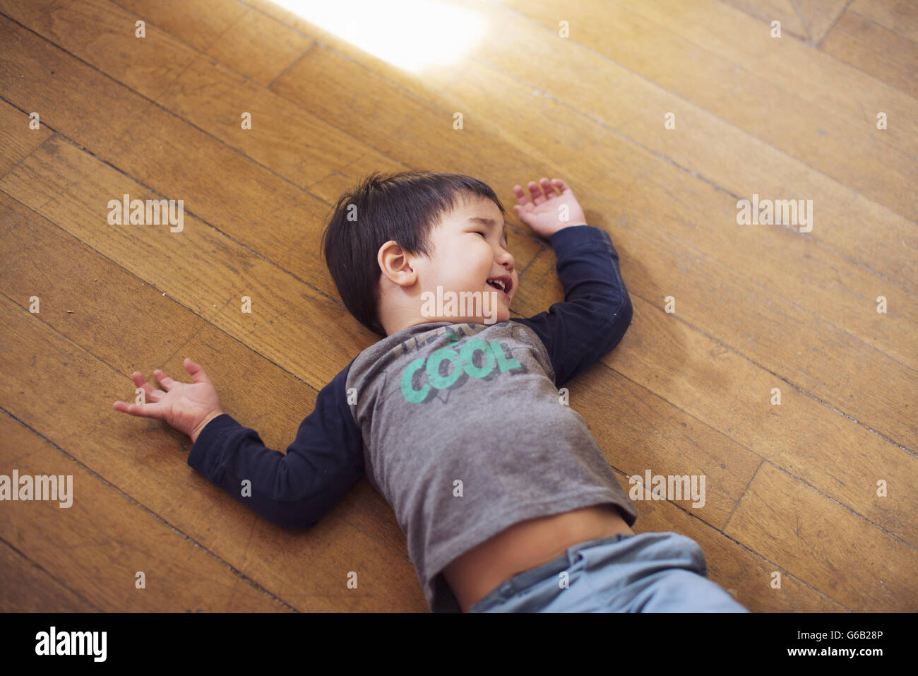 Little boy lying on floor laughing Stock Photo
