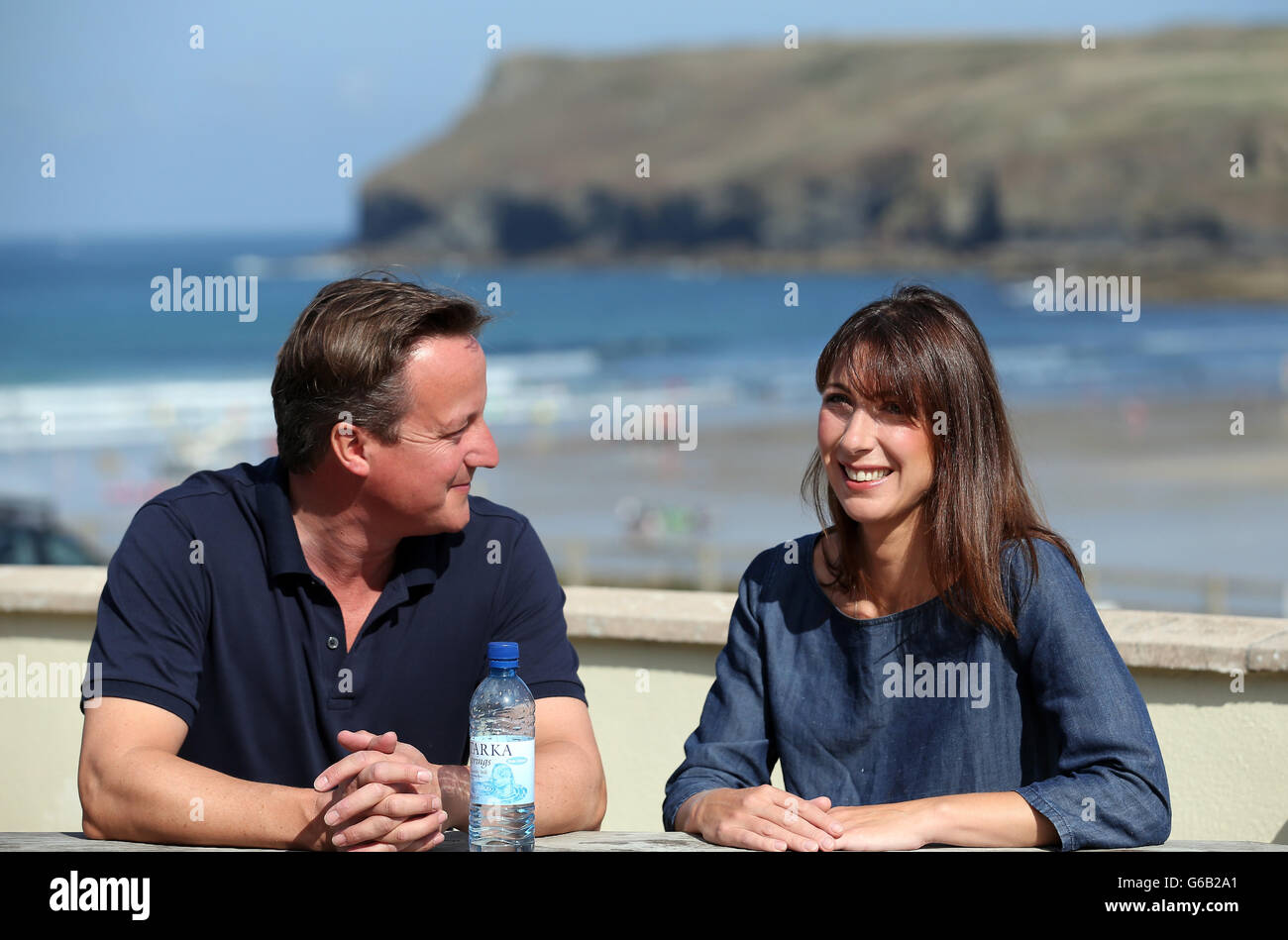 Prime Minister David Cameron and his wife Samantha sit on a bench outside a cafe overlooking the beach at Polzeath during their summer holiday in North Cornwall. Stock Photo