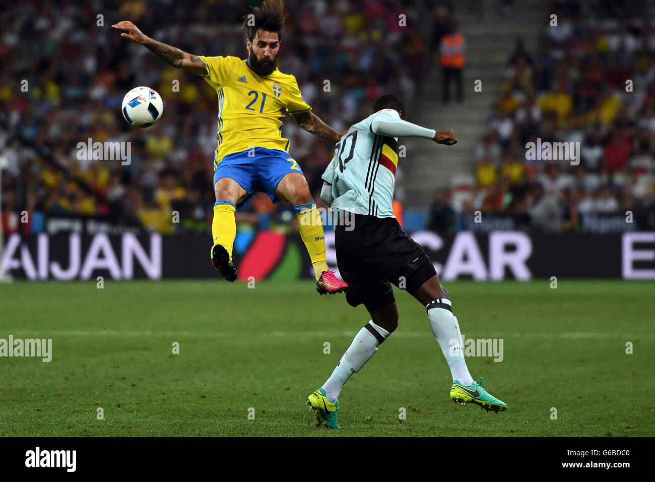 Nice, France. 22nd June, 2016. Sweden's Jimmy Durmaz (L) challenges for the ball with Belgium's Christian Benteke during the UEFA Euro 2016 Group E soccer match between Sweden vs at the Stade de Nice in Nice, France, 22 June 2016. At right German Referee Felix Brych. Photo: Federico Gambarini/dpa/Alamy Live News Stock Photo