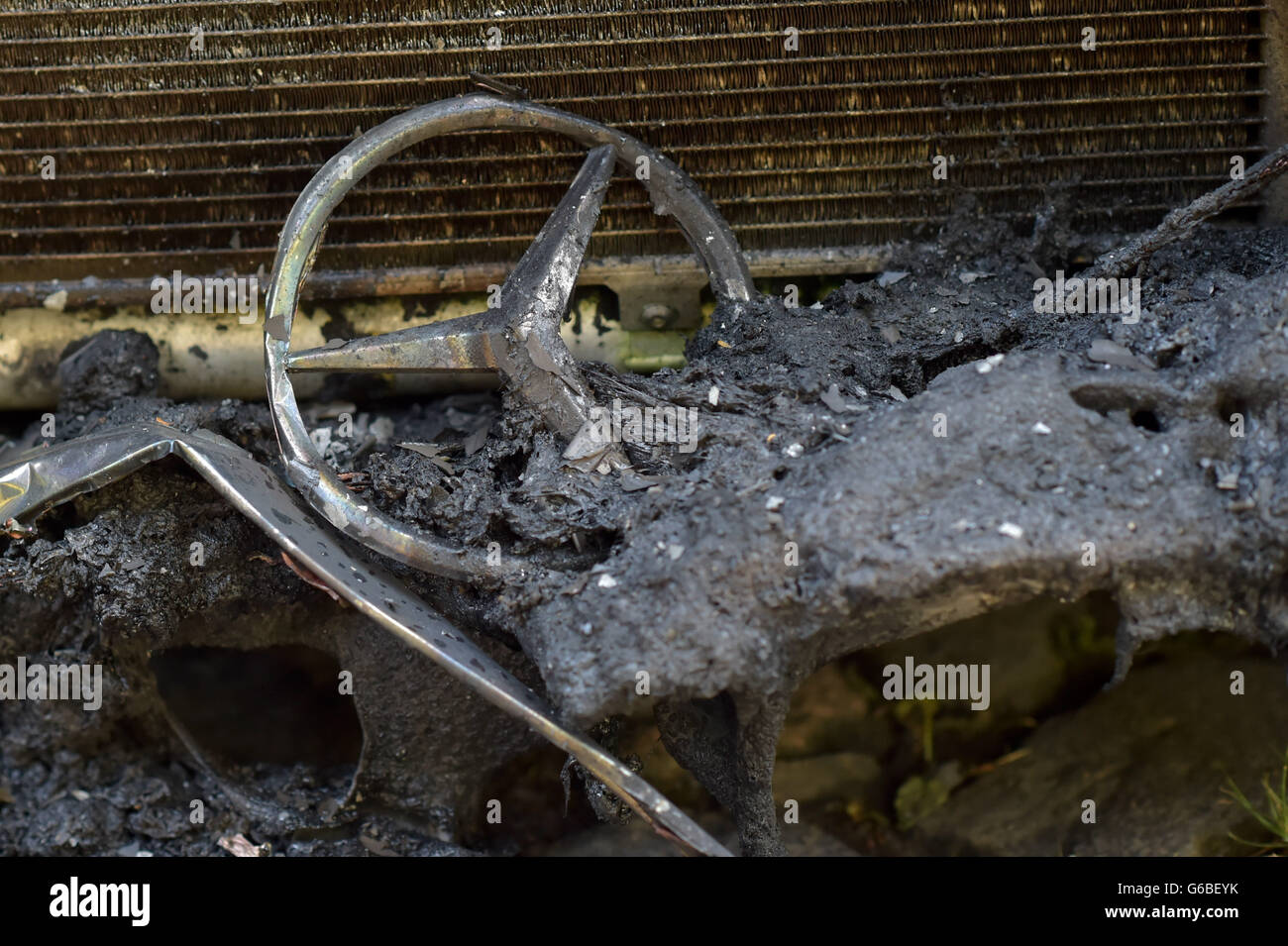 Berlin, Germany. 24th June, 2016. The star of a Mercedes lying in the ashes of a burnt out car in Berlin, Germany, 24 June 2016. After a police operation at Rigaer Strasse on 22 June, cars were lit on fire for the second night in a row. PHOTO: KLAUS-DIETMAR GABBERT/dpa/Alamy Live News Stock Photo