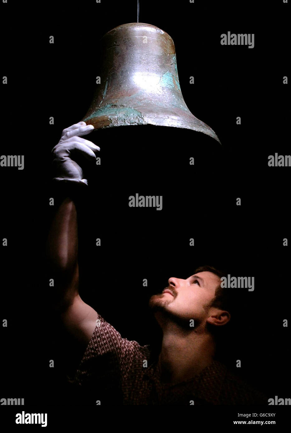 Tom Zaller, production manager of the Titanic Artifact Exhibition at the Science Museum in west London, puts up the bell from the crows nest of the Titanic. The ship's bell, rung moments before the liner struck an iceberg, *..and is part of the exhibition which opens to the public on May 16. Stock Photo