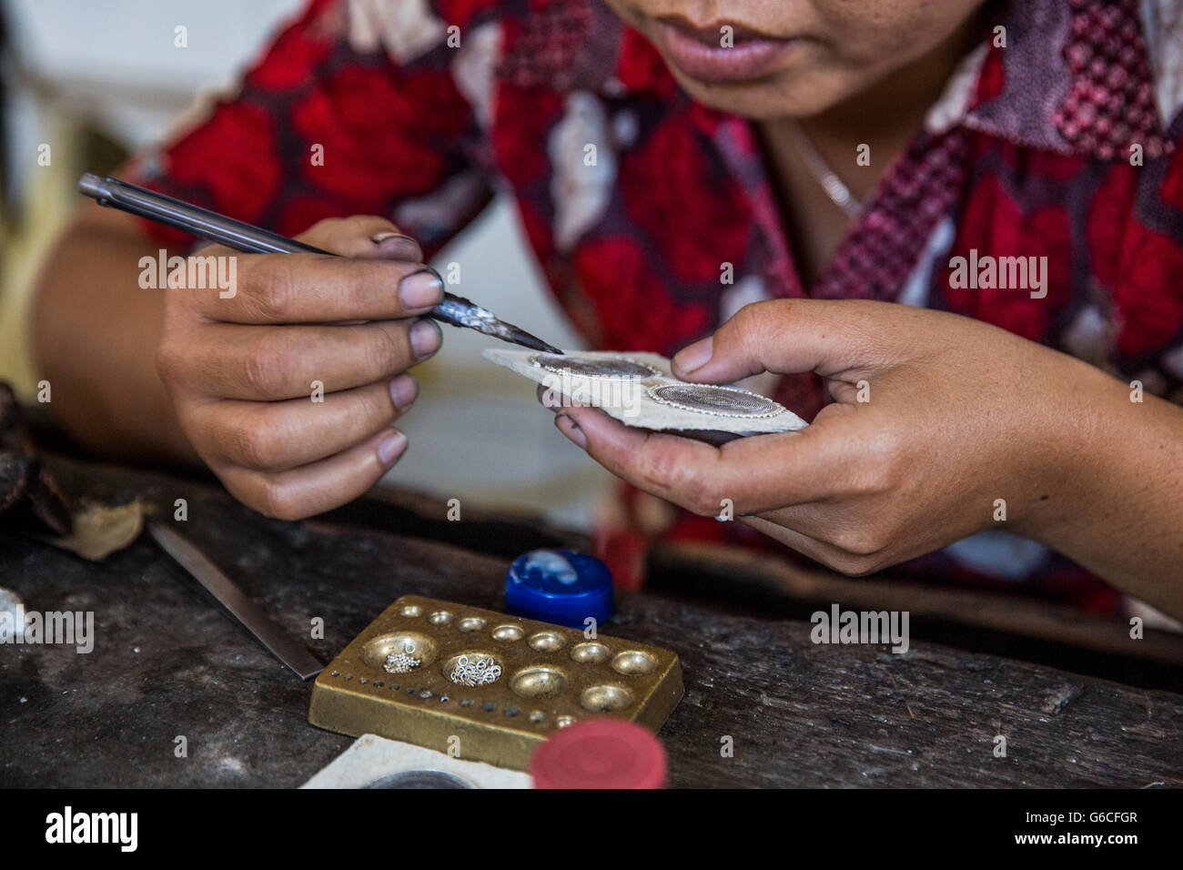 An Indonesian woman makes silver jewelry by hand in her studio in Ubud, Bali. Stock Photo