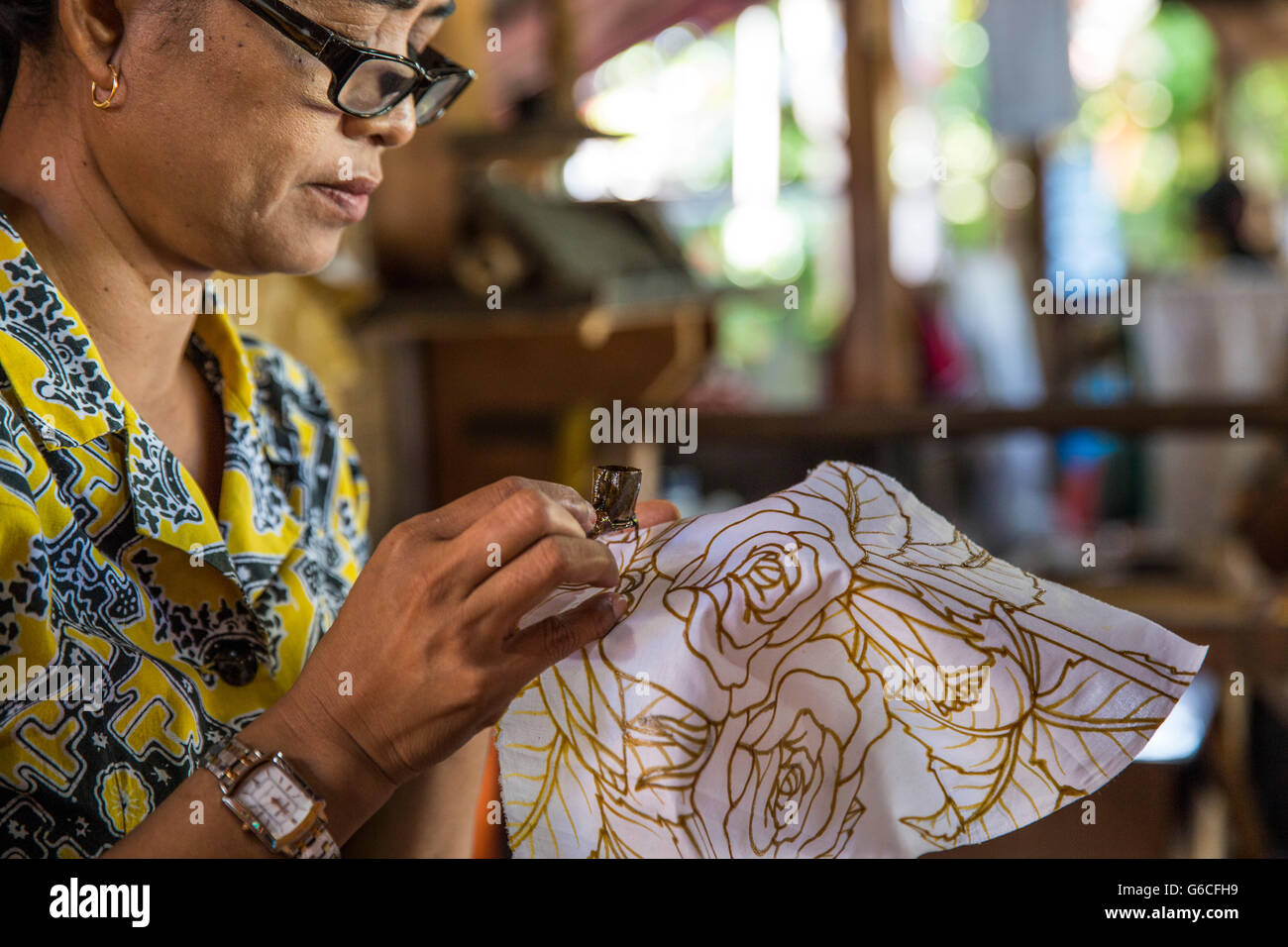 An Indonesian woman paints batik by hand in Ubud, Bali Stock Photo