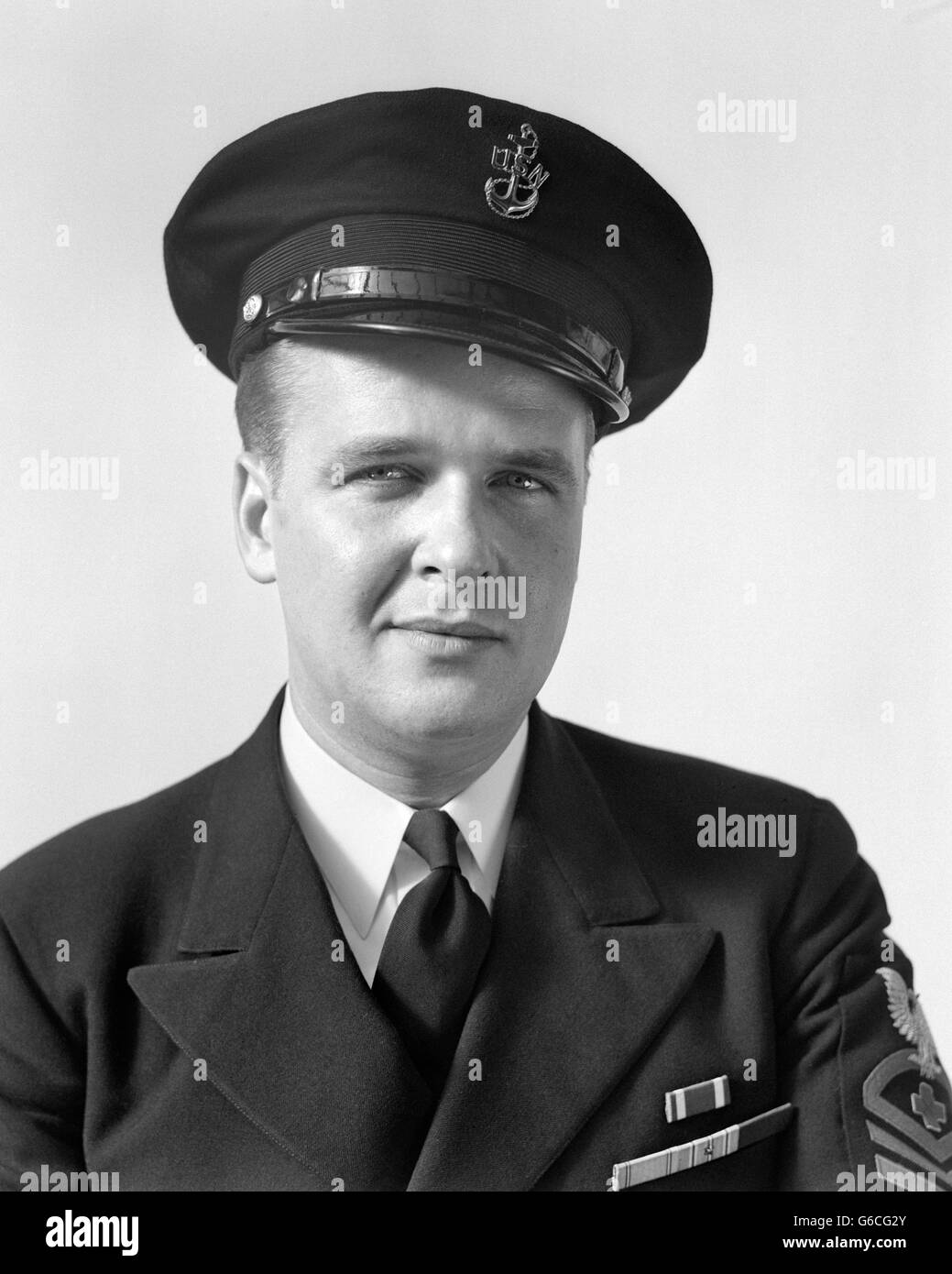 1940s PORTRAIT MAN VETERAN NAVY CHIEF PETTY OFFICER IN UNIFORM AND HAT LOOKING AT CAMERA Stock Photo