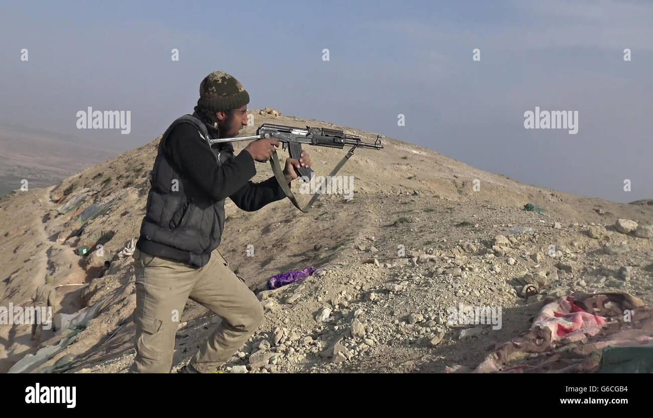 Islamic State fighter fires an Ak-47 during fighting in the Makhoul Mountains May 30, 2016 near Baiji, Iraq. The still image is captured from a propaganda video released by the Islamic State of Iraq and the Levant. Stock Photo