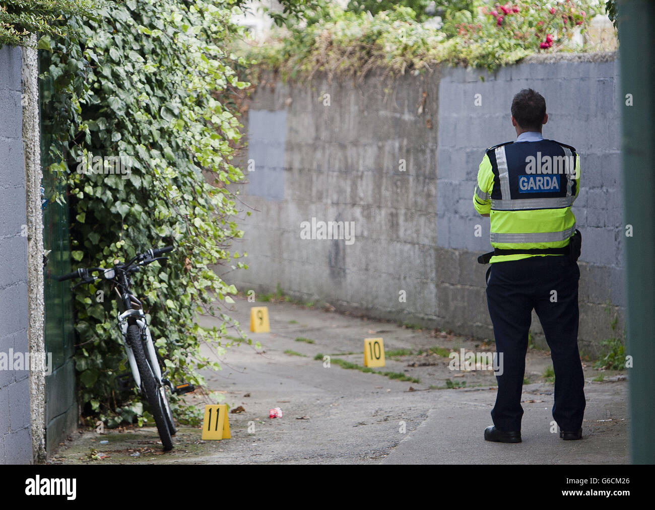 A Garda stands in the alley way between Glasnevin Ave at Glasnevin Park of North Dublin where a man in his mid 60's was shot. Picture date: Monday 26 August, 2013. See PA story POLICE Shooting Ireland. Photo credit should read: Liam McBurney/PA Wire Stock Photo