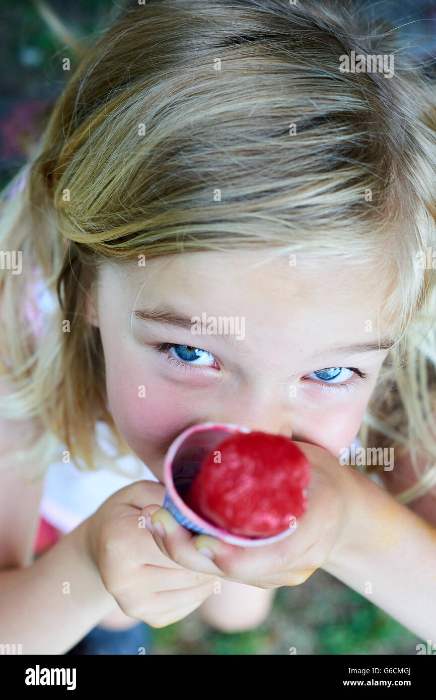 Beautiful little blond girl eats ice-cream in the summer Stock Photo