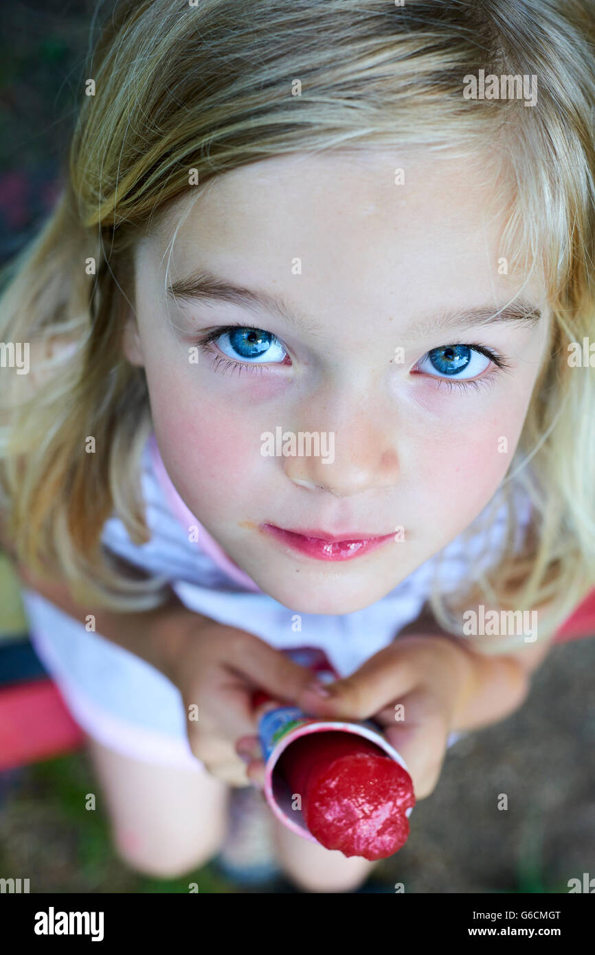 Beautiful little blond girl eats ice-cream in the summer Stock Photo