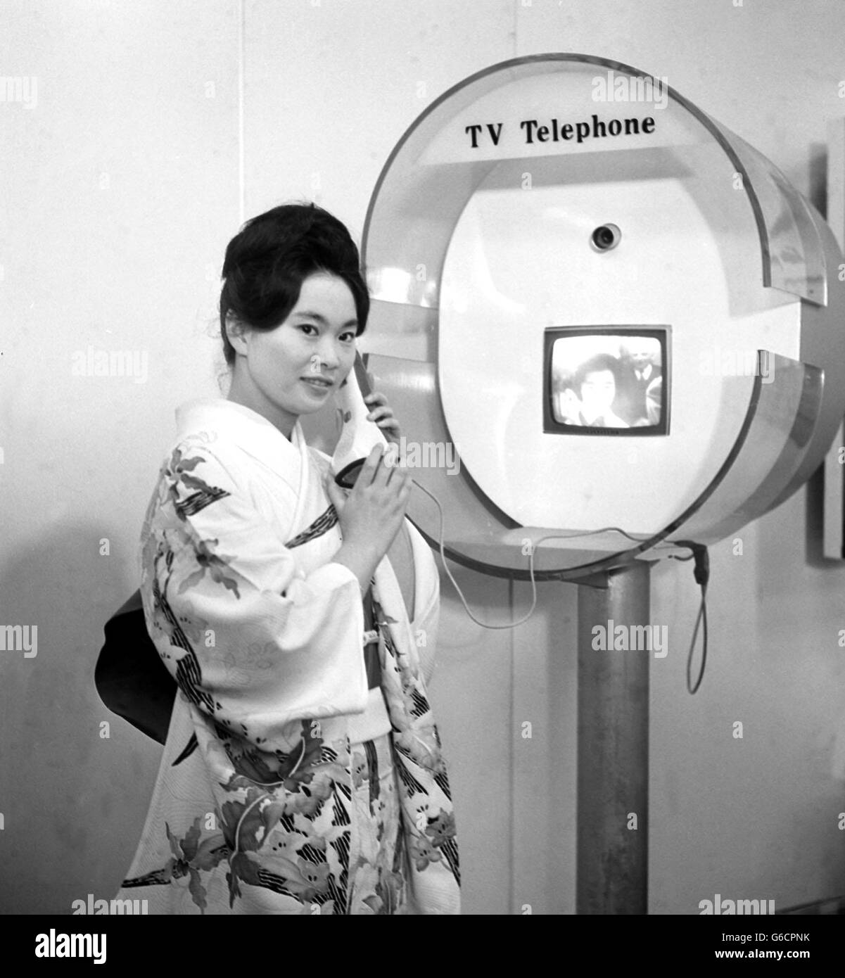 On this day in 1964 a floating Japanese Trade Fair docked at Tilbury docks. Twenty-Two-year-old Fusako Okado, from Kyoto, Japan, demonstrates with a colleague a new television system telephone installed on board the Sakura Maru moored at Tilbury, Essex. Stock Photo