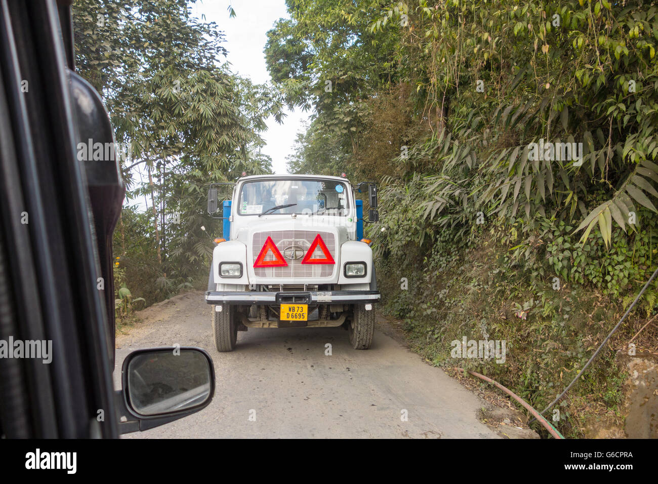 View from car passenger seat - A Tata truck approaches from front while on a narrow road in Darjeeling, West Bengal, India Stock Photo