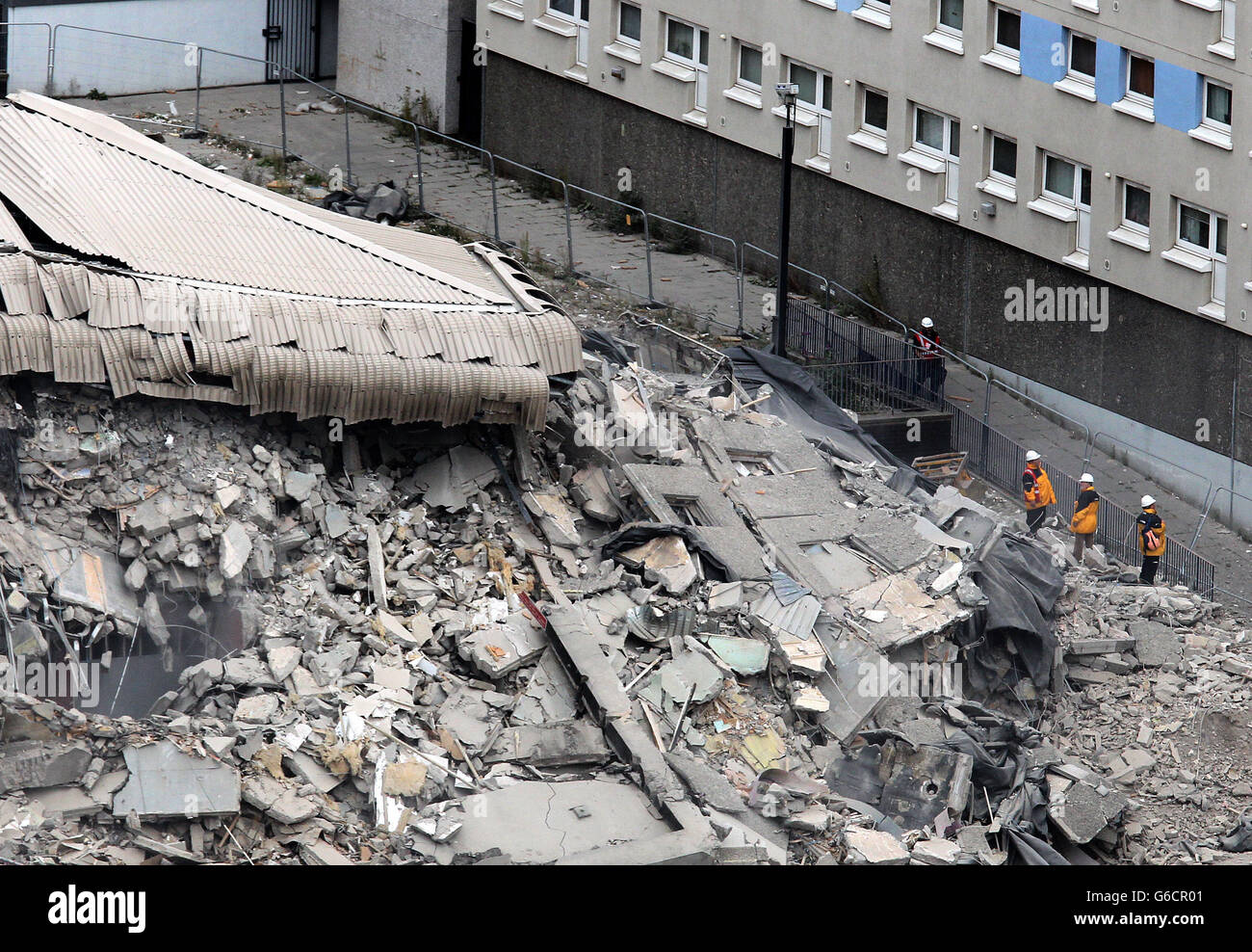 Workmen view the rubble after the demolition of a 18-storey tower block ...