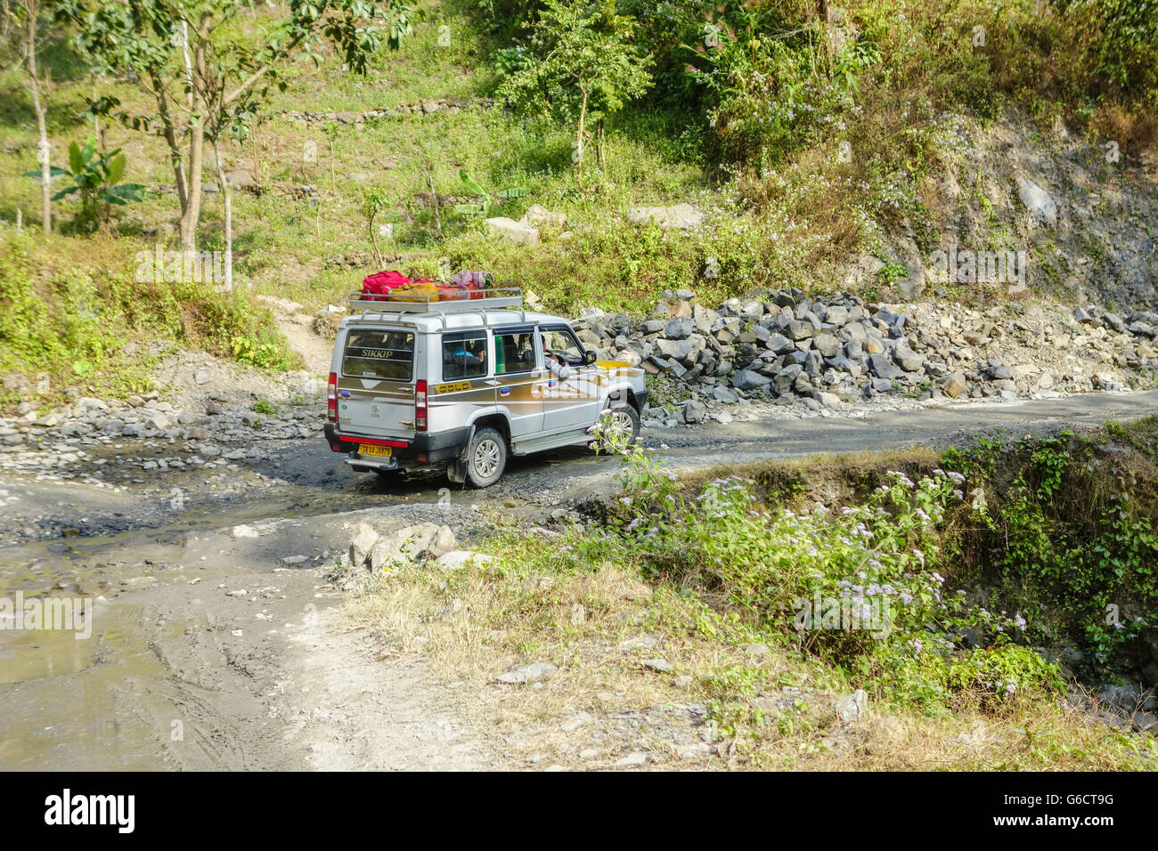 A Tata Sumo taxi takes on a bad patch of marshy, muddy road en route to Pelling in Sikkim from Darjeeling, West Bengal, India Stock Photo