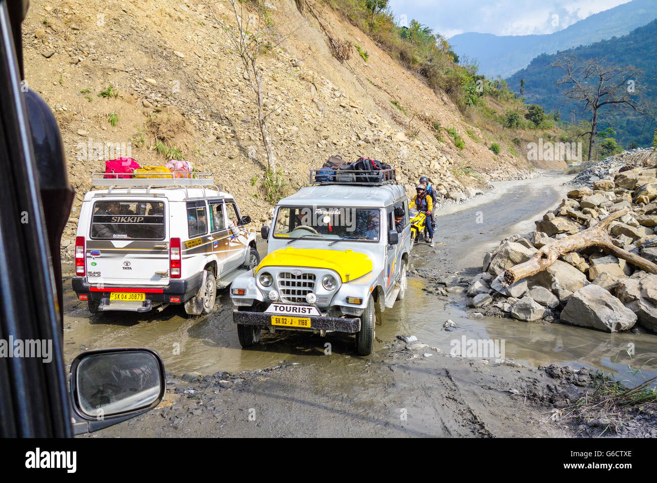 Two tourist SUV taxis cross on a bad patch of marshy, muddy road en route to Pelling in Sikkim from Darjeeling, West Bengal Stock Photo