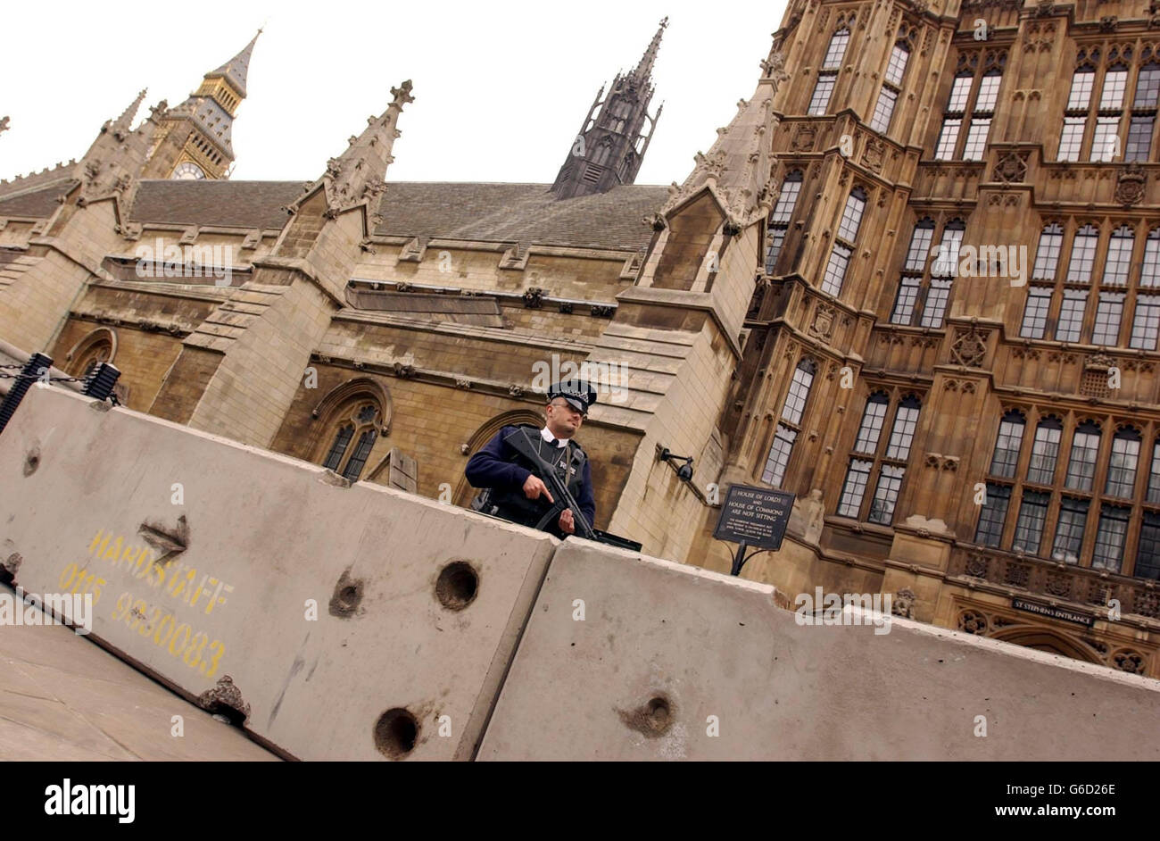An armed policeman stands infront of the new concrete blocks, placed outside the Palace of westminster, London, to protect against a possible attack from terrorist vehicles. * The concrete blocks have been put in place for the nine-day Whitsun recess which begins, parliamentary officials said. Stock Photo