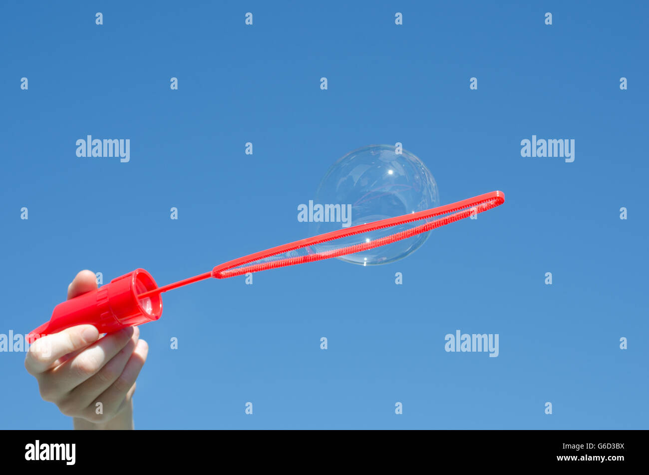 Blowing bubbles on a sunny day against blue sky Stock Photo