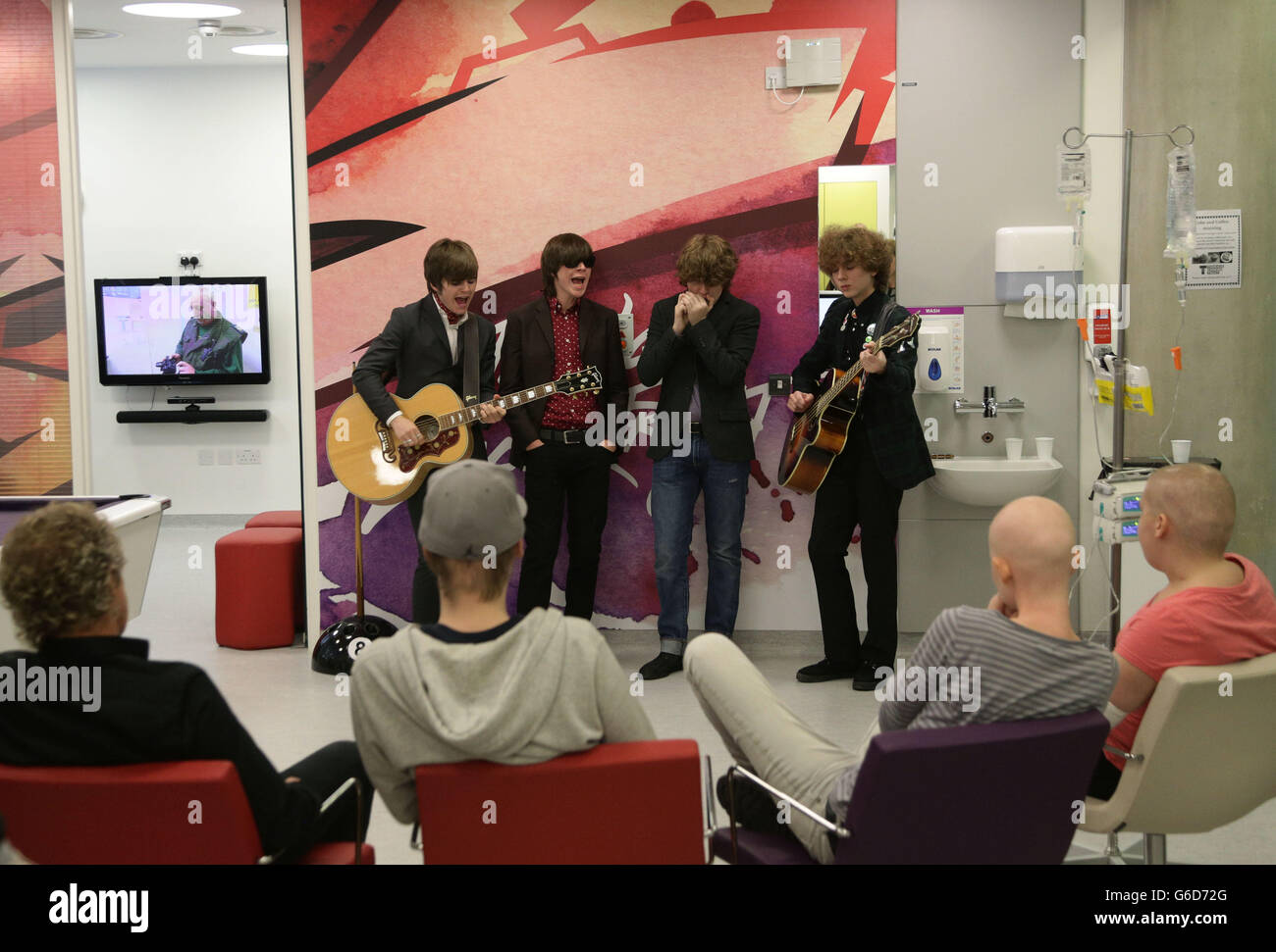 Roger Daltrey CBE (left), Patron of Teenage Cancer Trust, and current patients watching as R'n'B band The Strypes (left to right) Josh McClorey, Ross Farrelly, Pete O'Hanlon and Evan Walsh play during their visit and gig at a specialist Teenage Cancer Trust unit at University College Macmillan Cancer Centre, central London. Stock Photo