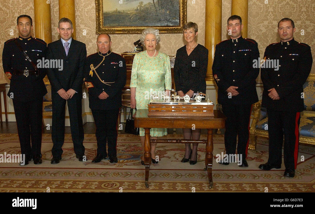 Britain's Queen Elizabeth II with Sergeant Major Derek Gilbert (far left) and Mrs Karen Bower (Advisor, London District) with a silver centre piece commissioned by the Royal Regiment of Artillery, also pictured are representatives of the Warrant Officers and Sergeants at Buckingham Palace. Stock Photo
