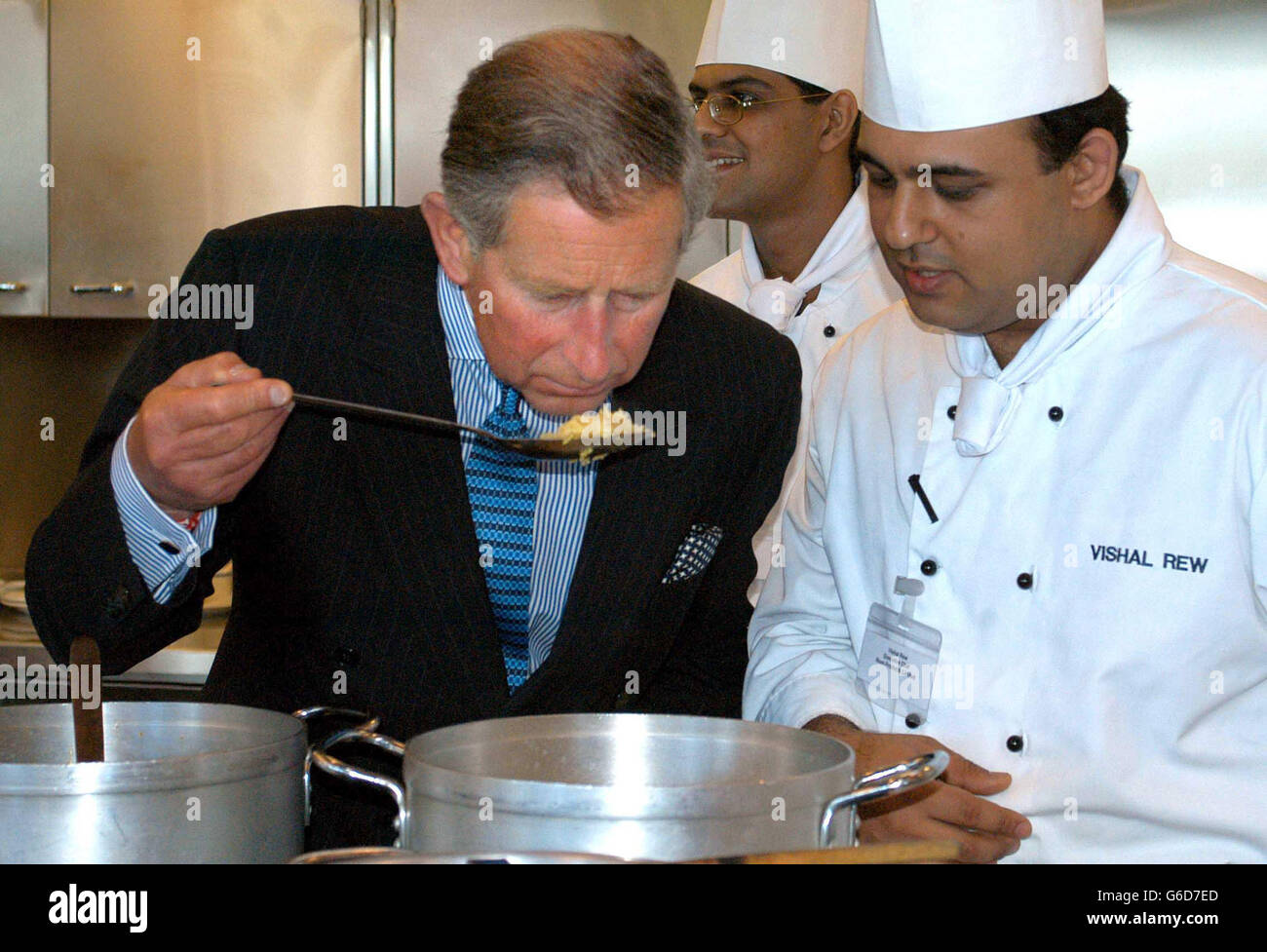 The Prince of Wales during his visit at Noon Products in Southall. Dressed in a pin-striped suit with a stripy shirt and pale blue tie, the Prince laughed and joked with the chefs in the state of the art kitchen. * The Prince savoured the aroma from a cooking vat of Achari chicken, a hot pickled curry. Stock Photo