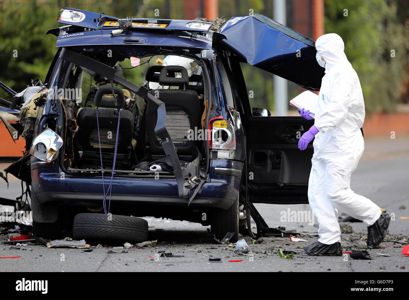 The remains of car is examined after bomb experts carried out a