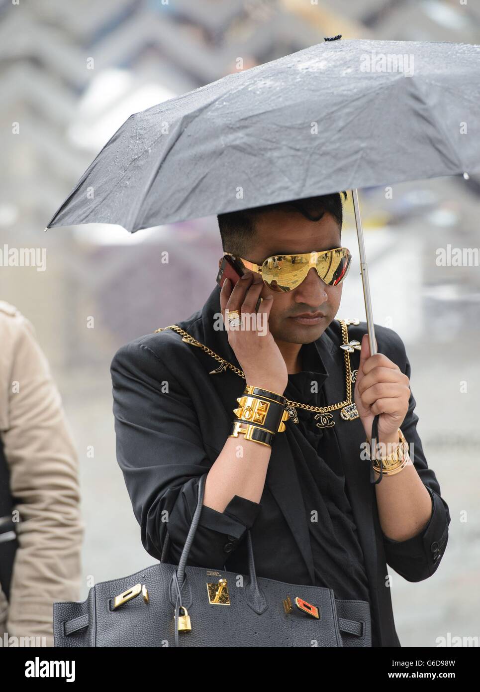 Arrivals - London Fashion Week 2013. An attendee shelters from the rain at Somerset House, central London, during London Fashion Week 2013. Stock Photo